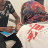 Arzt spricht mit Flüchtling in libyschem Internierungslager