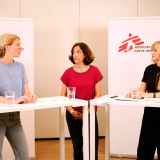 Drei Frauen stehen an Präsentationstischen und sprechen über ihre Forschung und Arbeit.