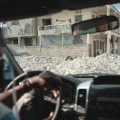 One of our employees is sitting in a car. In the background, there is visible destruction due to an earthquake.