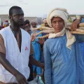 Ein junger Mann mit Material für eine Notunterkunft und ein Mitarbeiter von Ärzte ohne Grenzen in Mali.