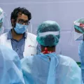Vier Ärzte beraten sich. Sie sind komplett in Schutzkleidung gehüllt.