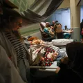 Behandelnde und Angehörige am Bett einer Patientin.