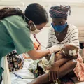 Ärztin versorgt Baby in Krankenbett