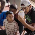 Denguefieber in Honduras: Mann und Jungen blicken in Glas mit Mücken.