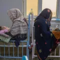 Zwei Frauen sitzen mit ihren Babys auf dem Schoss auf Betten