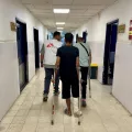 Mitarbeitende und Patient auf Krücken in Krankenhausgang