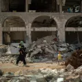 Frau trägt Kind durch Trümmer in Gaza-Stadt.