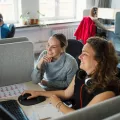 Zwei Mitarbeitende am Schreibtisch vor dem Computer