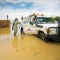 Einer unserer Geländewagen im Hochwasser. Einige Mitarbeiter stehen neben dem PKW.