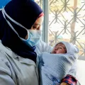Hebamme hält Baby im Arm