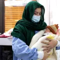 Eine Mitarbeiterin in Pakistan hält ein Neugeborenes auf ihrem Arm.
