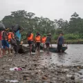 Menschen mit Rettungswesten steigen in ein Kanu auf einem Fluss ein