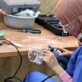 Eine Frau modelliert eine Kunststoffmaske mit einem Schleifgerät
