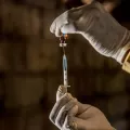 Zwei Hände die Impfstoff in eine Spritze ziehen