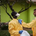 Hygienespezialist hilft Kollege in Schutzkleidung