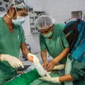 Operationsaal: Arzt und HelferInnen operieren.