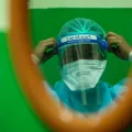 Eine medizinische Fachkraft passt den Gesichtsschutz an, bevor sie die Station betritt.