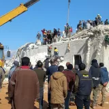 Menschen stehen vor einem zerstörten Gebäude