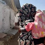 Frau mit Kopftuch hält Kind auf dem Arm