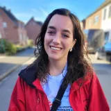 Ein Portrait auf dem eine Frau lächelt und eine Jacke und T-Shirt von Ärzte ohne Grenzen trägt.