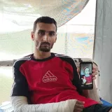 Ein Mann mit eingegipsten Arm hält ein Handy hoch, das das Bild eines Mädchens zeigt