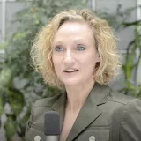 Eine blonde Frau spricht in ein Mikrophon